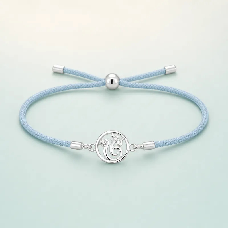 Stylised Om / paisley swirl charm, light blue cord  -  925 Sterling Silver on seaglass background