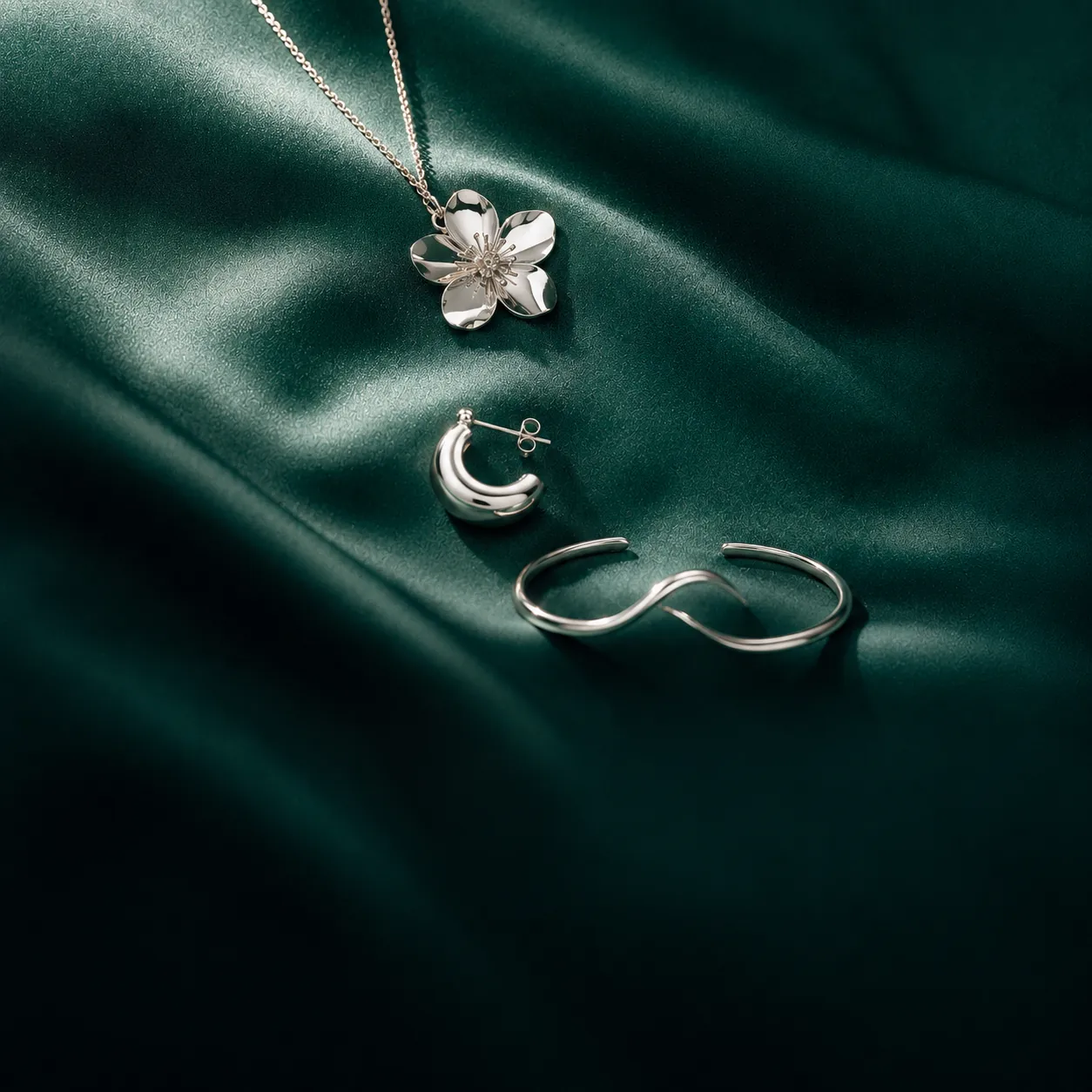 Three DIYAM sterling silver pieces in a diagonal line on emerald silk
