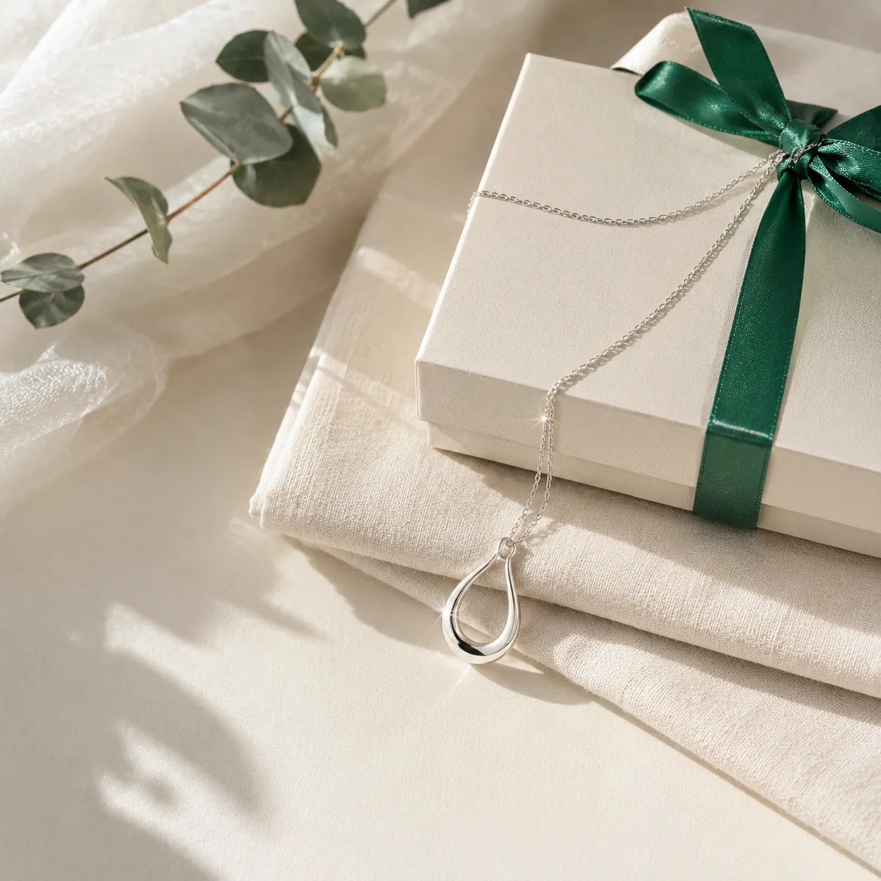 An open emerald jewellery box with a silver pendant and a hand-written ivory ribbon